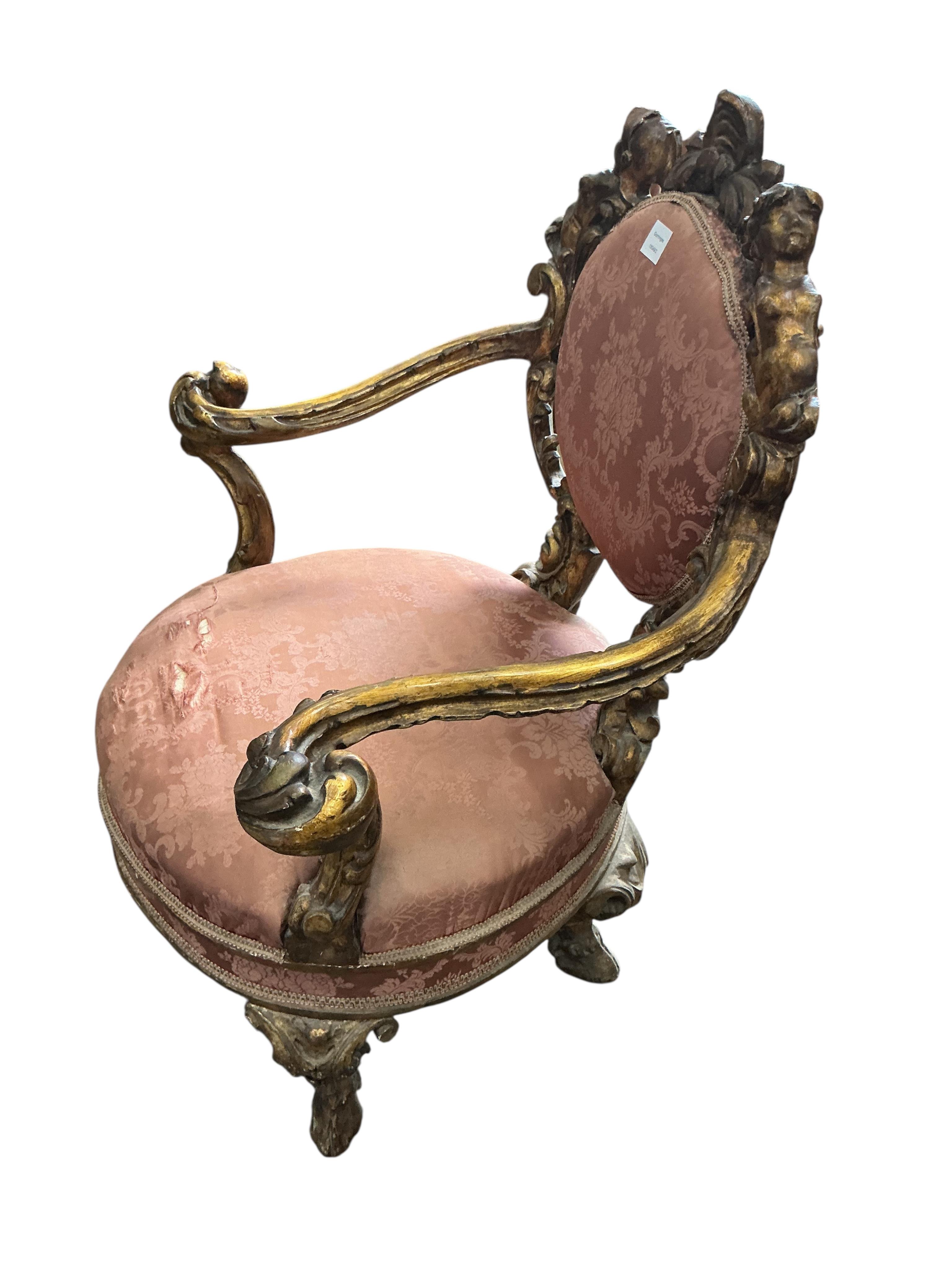 A 19th century Italian parcel gilt baroque revival armchair decorated with caryatids and leaf scrolls, upholstered in pink damask, fabric torn, width 80cm, depth 60cm, height 90cm